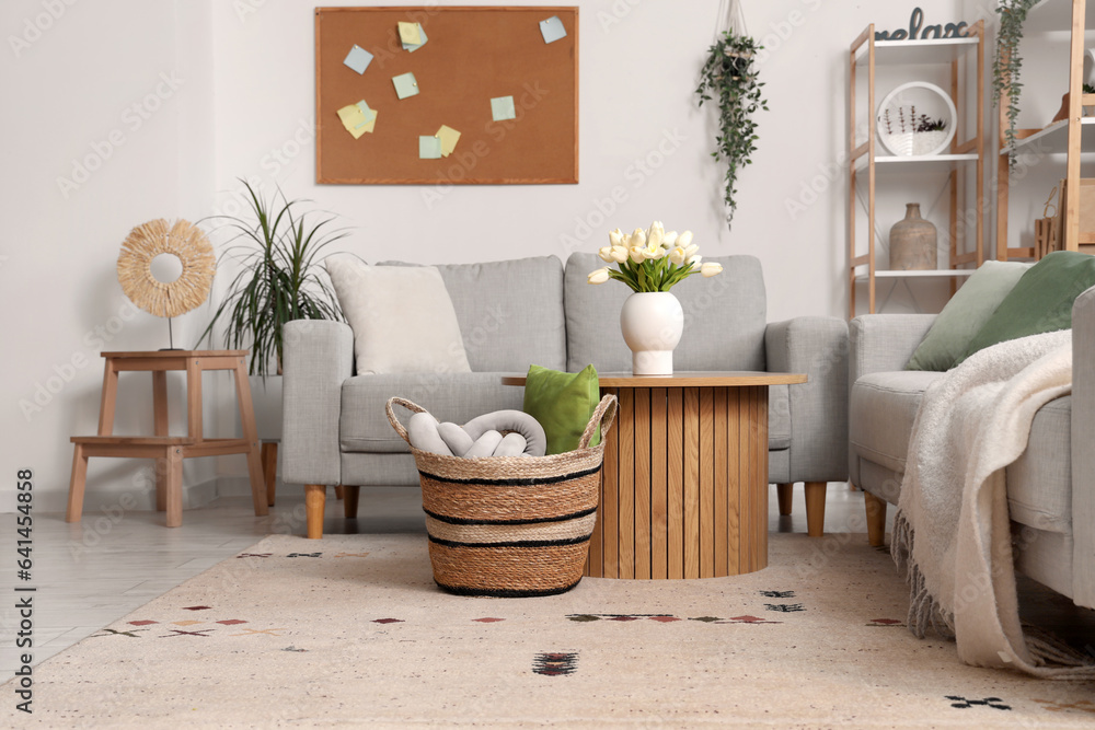 Interior of light living room with sofas, table and wicker basket