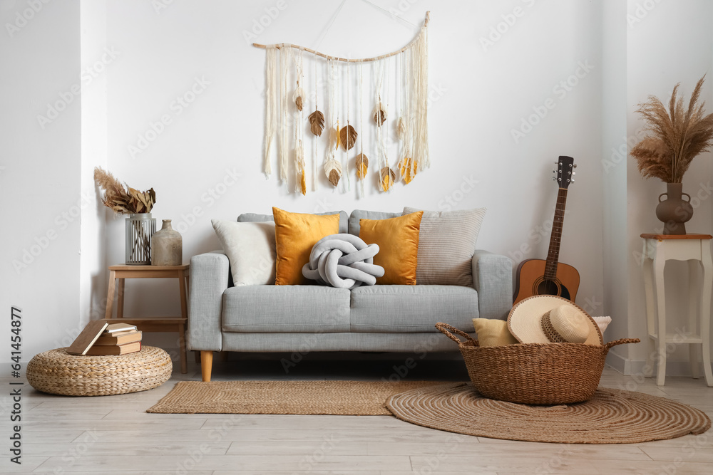 Interior of light living room with sofa, wicker basket and guitar