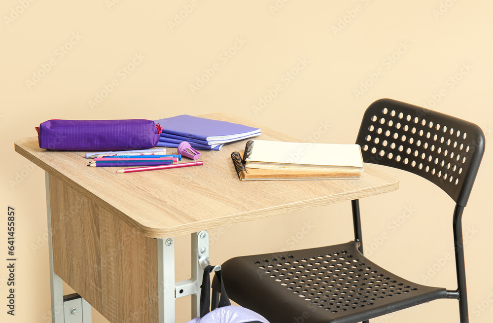 Modern school desk with stationery on beige background