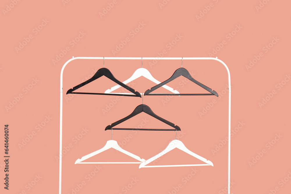 Rack with wooden clothes hangers on pink background