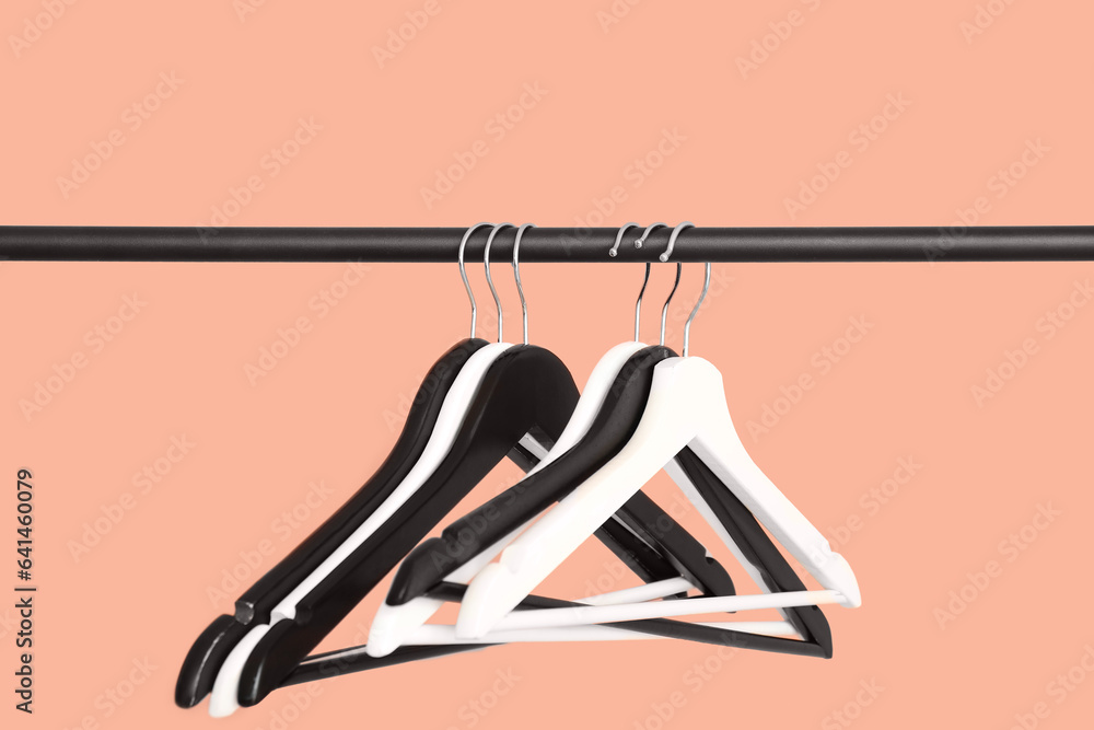 Rack with wooden clothes hangers on pink background