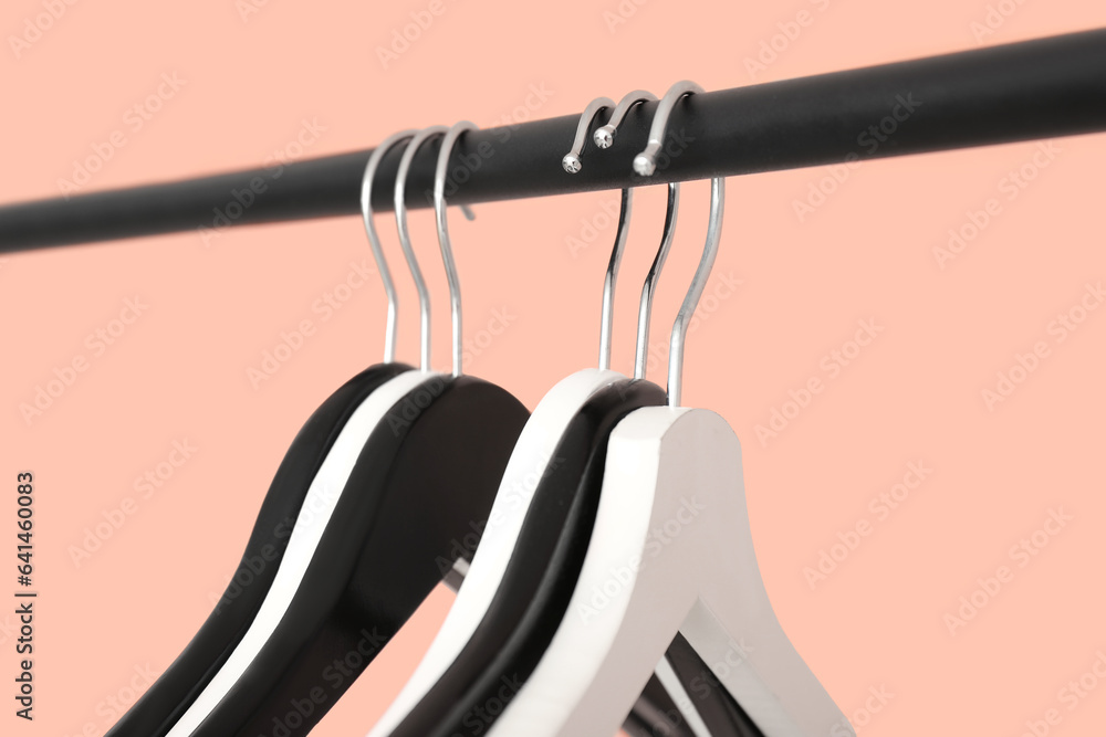 Rack with wooden clothes hangers on pink background