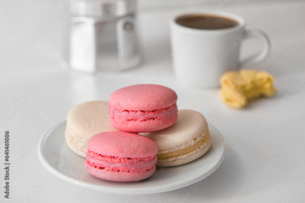 Plate with sweet macaroons on white background