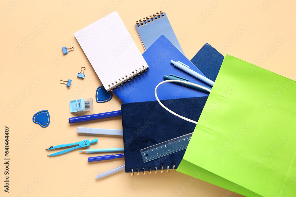 Paper bag with stationery on color background