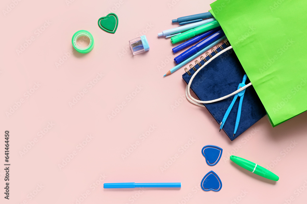 Composition with paper bag and different stationery on pink background