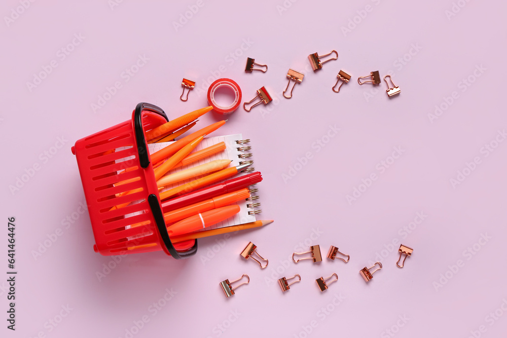 Composition with different stationery and shopping basket on pink background