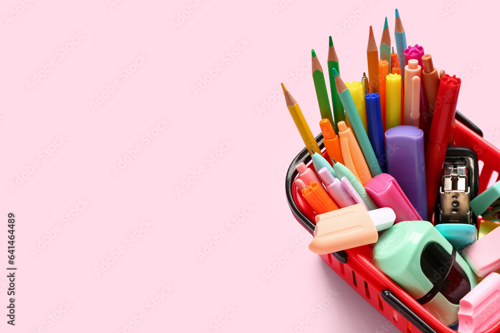 Shopping basket with different stationery on pink background