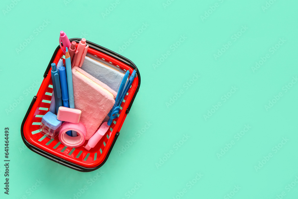 Shopping basket with different stationery on color background