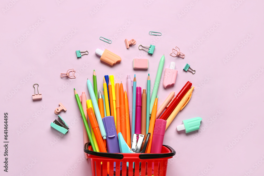 Composition with shopping basket and different stationery on pink background