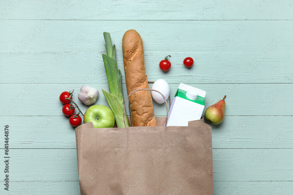 Paper bag full of fresh products on green wooden background