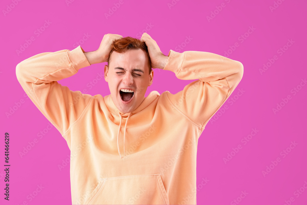 Stressed young redhead man on purple background