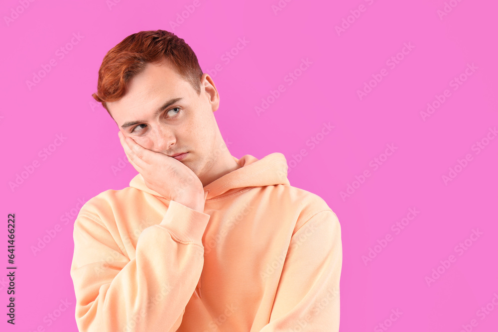 Tired young redhead man on purple background