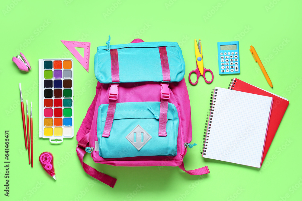 Stylish school backpack and different stationery on green background