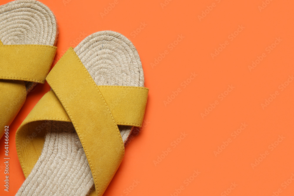 Stylish yellow sandals on orange background