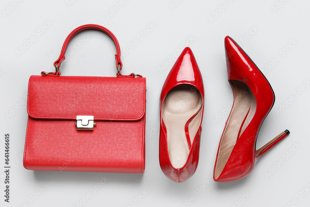 Stylish red high heels and handbag on grey background