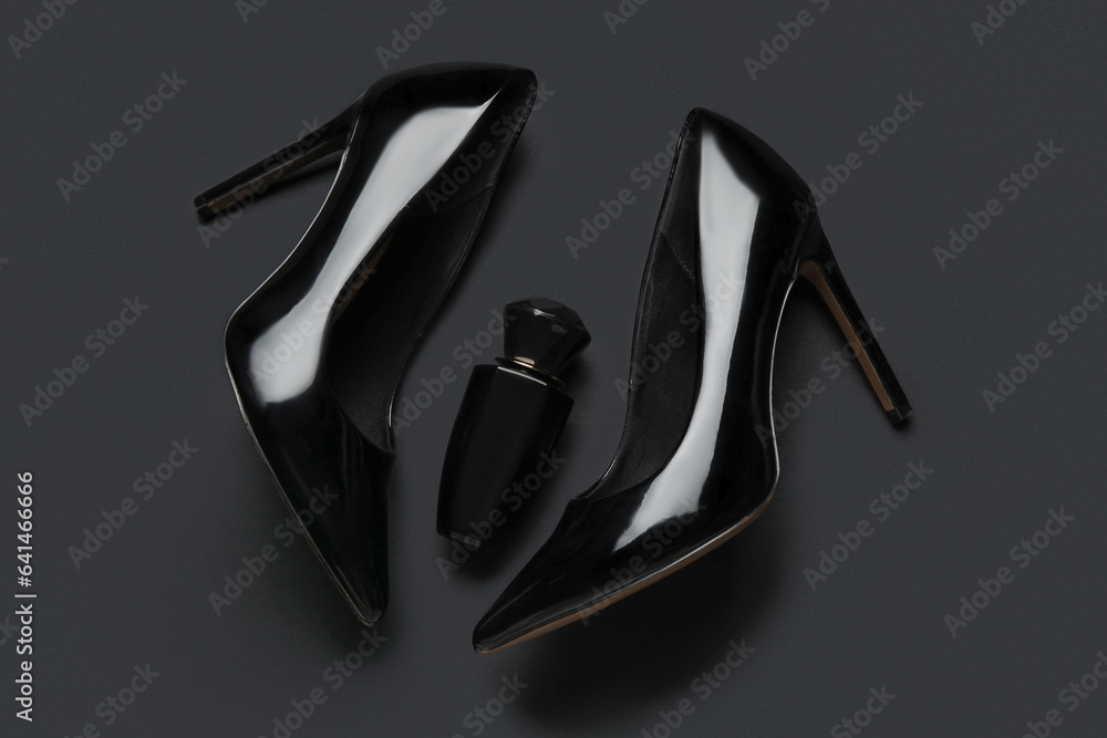 Stylish black high heels and perfume on color background