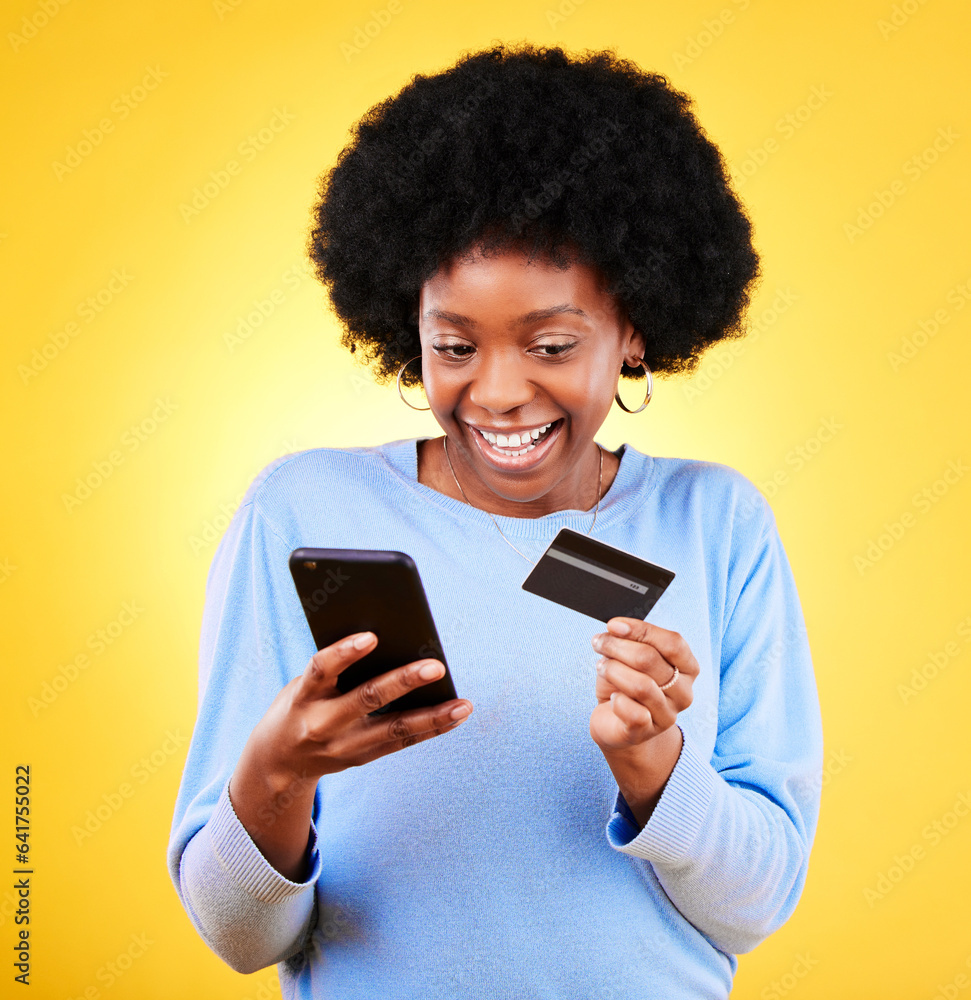 Happy black woman, phone and credit card in online shopping against a yellow studio background. Exci