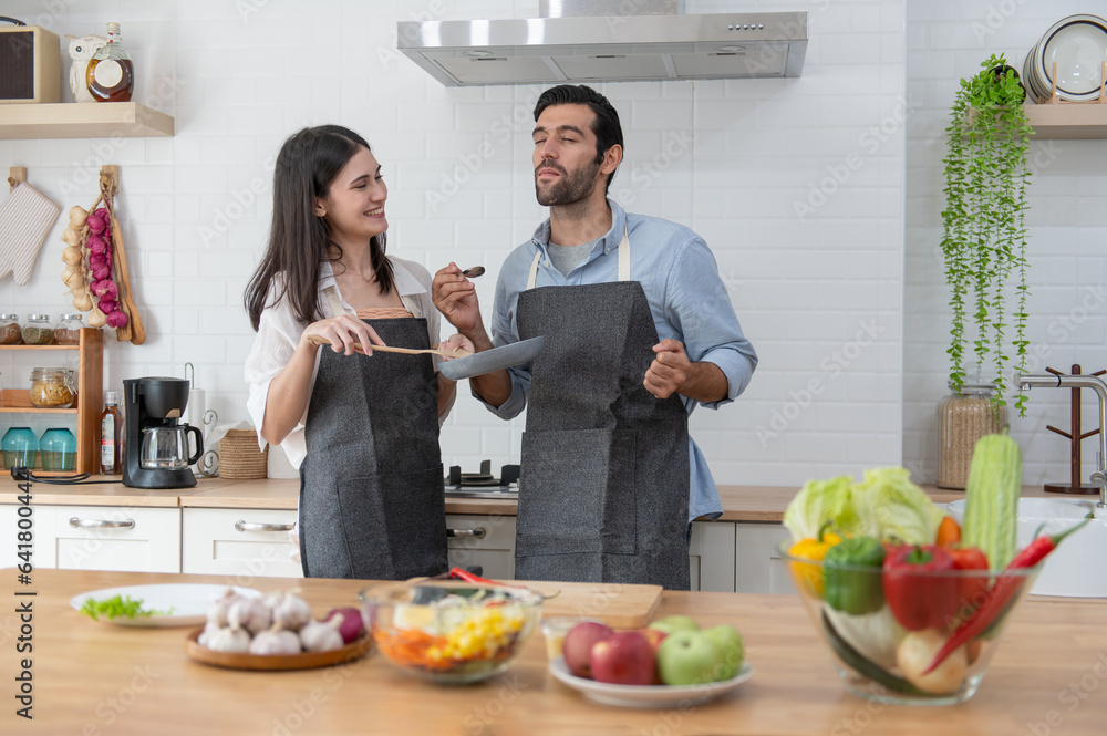 Happy young couple cooking together in the kitchen at home