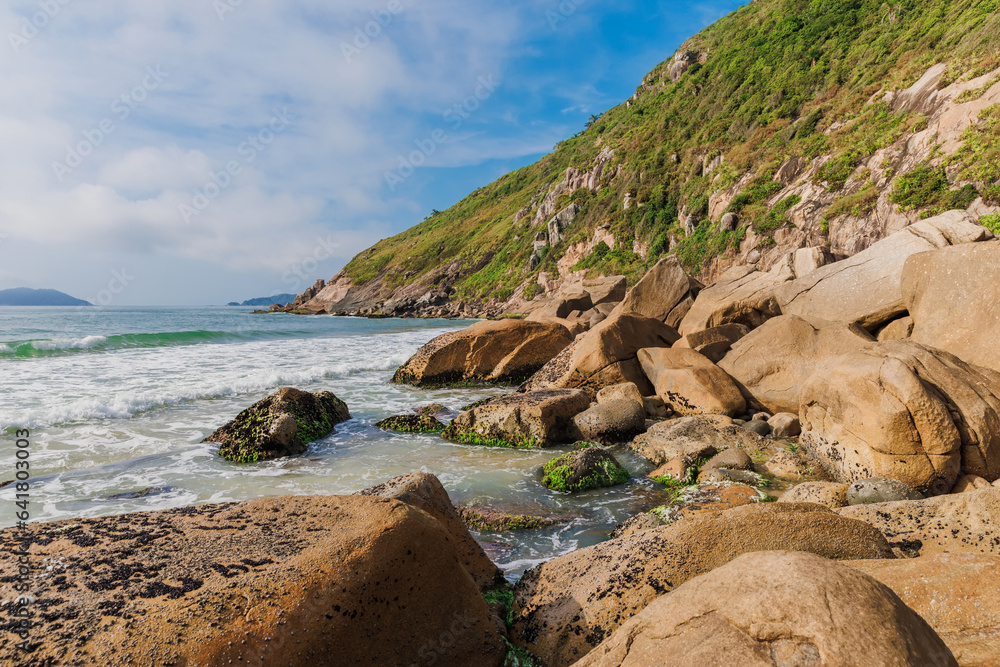 Beach with stones and ocean waves. Praia do Rio das Pacas in Florianopolis, Brazil