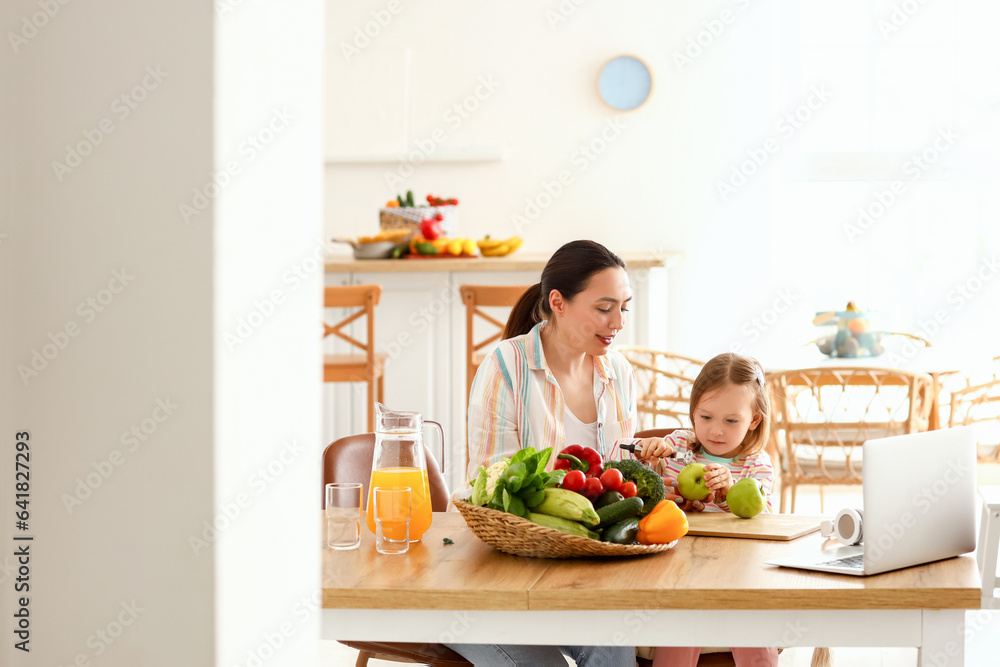 Little girl with her mother peeling apple in kitchen