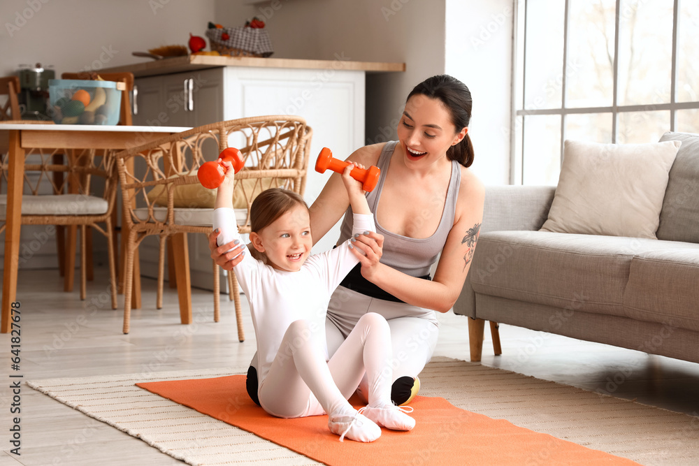 Sporty young woman with her little daughter training at home