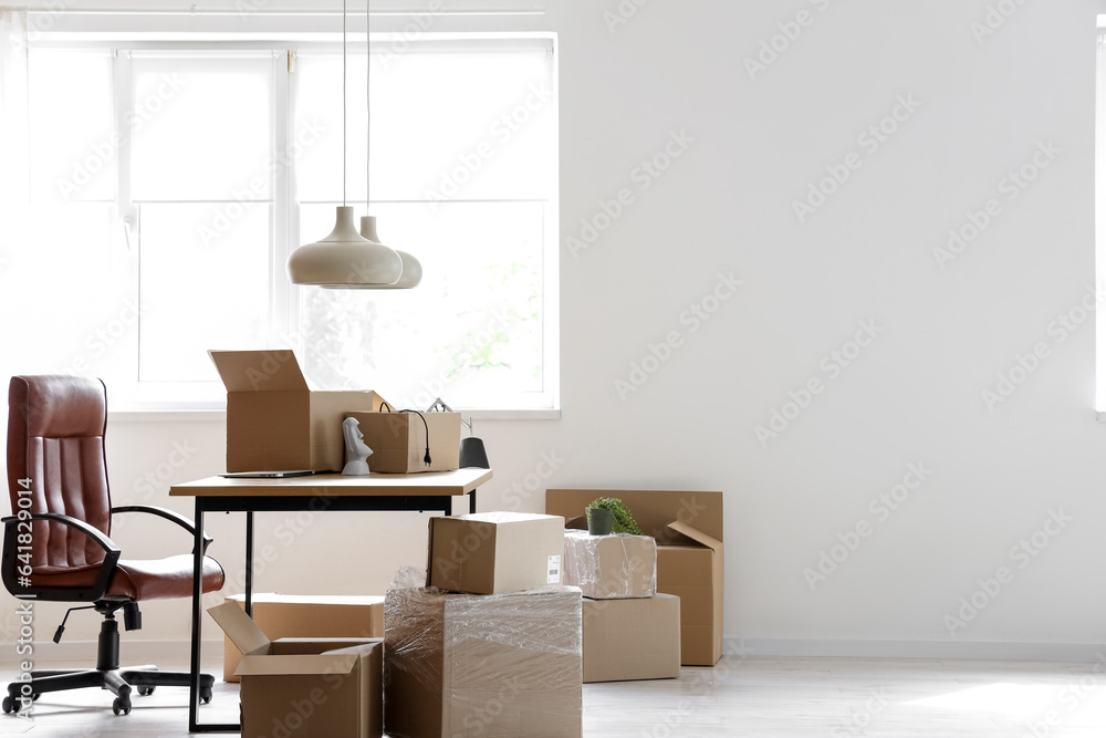 Interior of stylish office with cardboard boxes on moving day