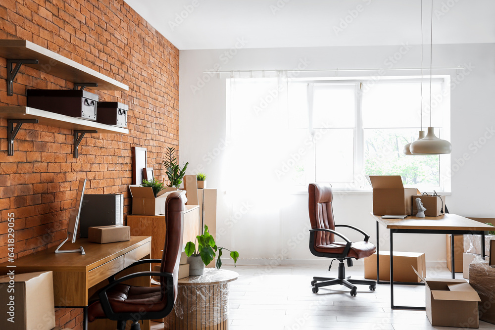 Interior of stylish office with cardboard boxes on moving day