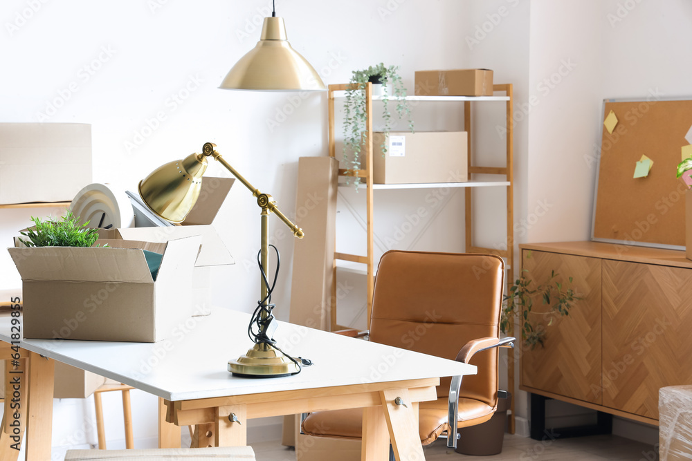 Modern workplace with lamp and cardboard boxes in office on moving day