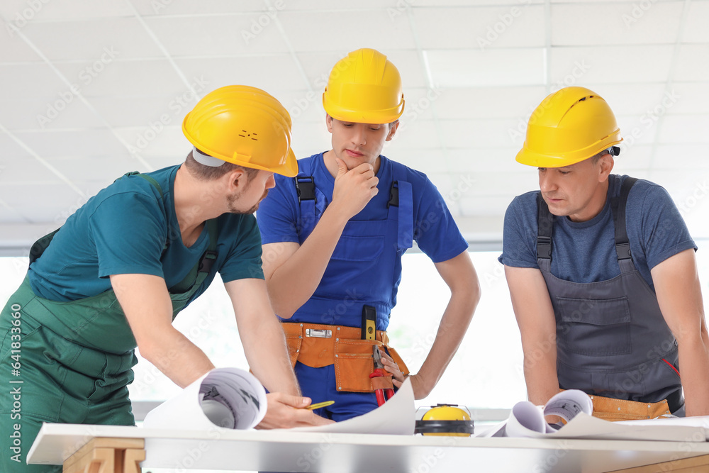 Team of male builders working with house plan in room