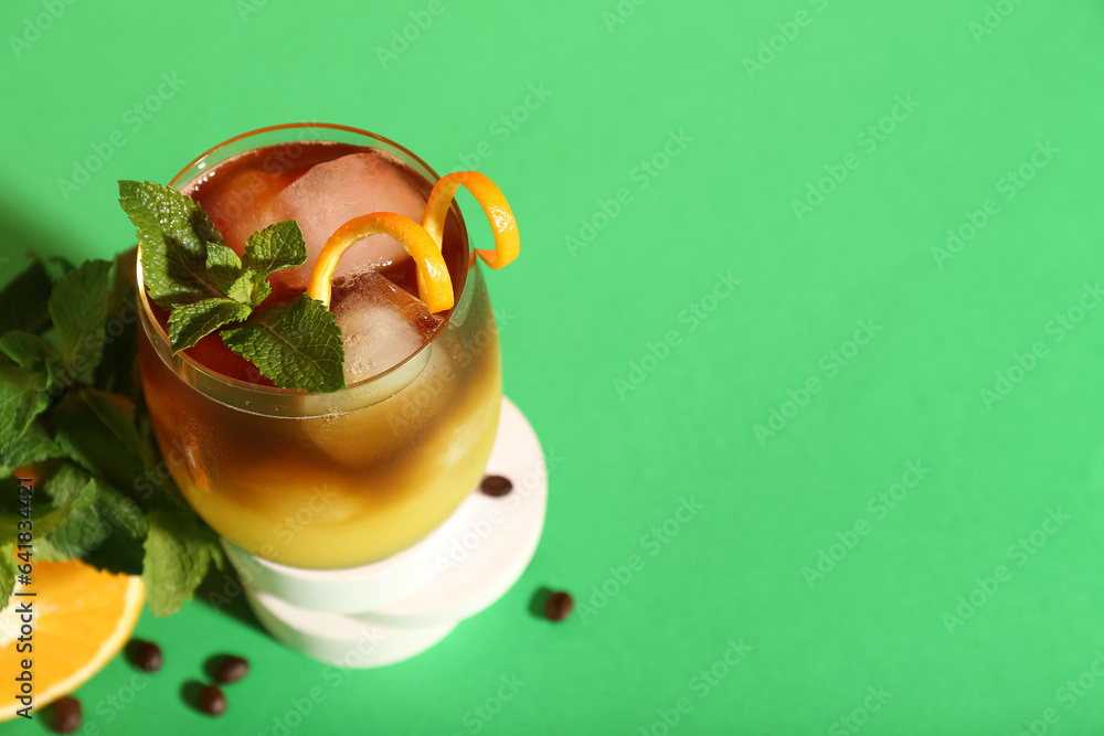 Glass of tasty orange espresso on green background