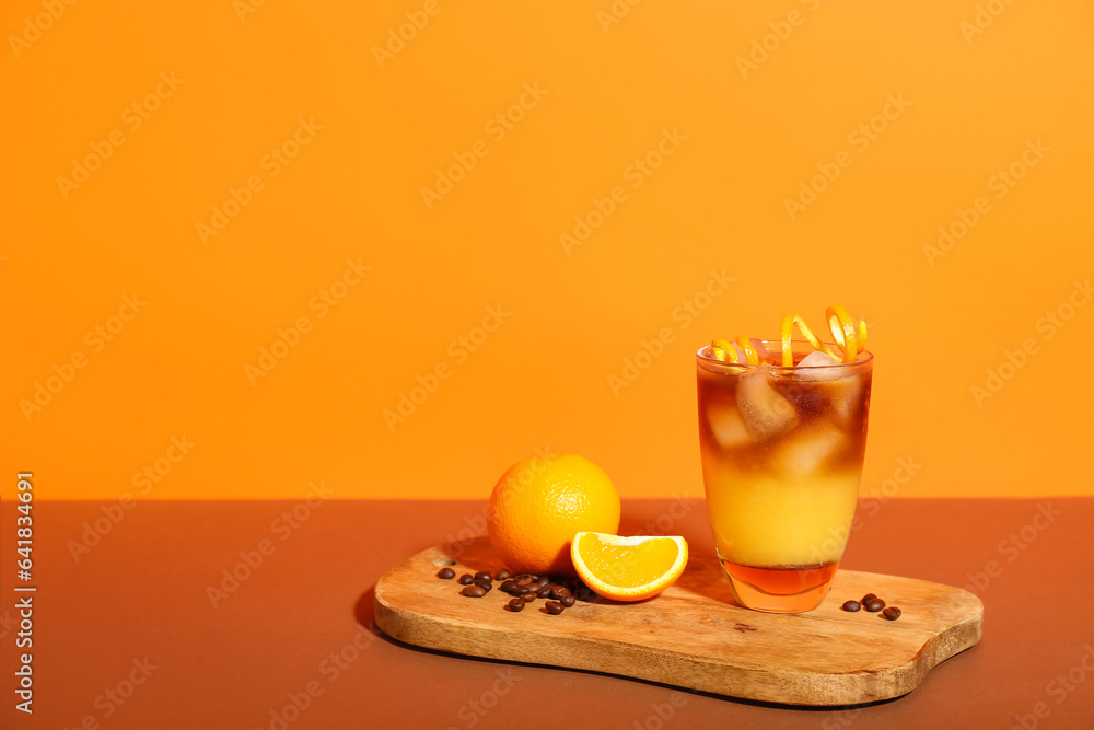 Glass of tasty orange espresso on color background