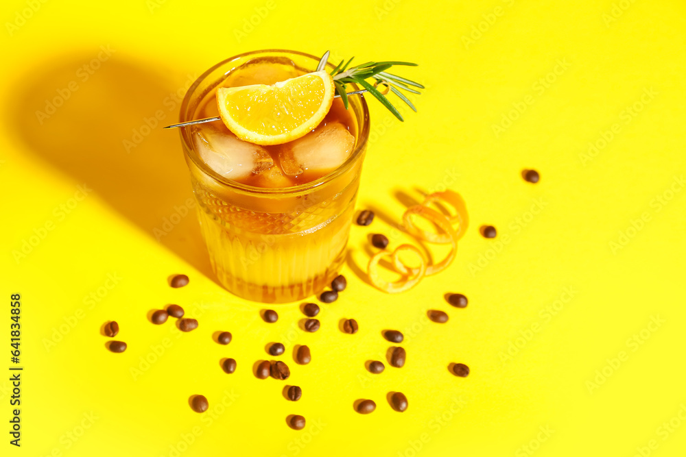 Glass of tasty orange espresso on yellow background