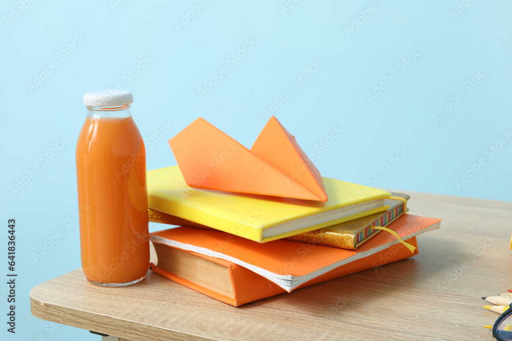 Modern school desk with lunch and stationery in room near blue wall