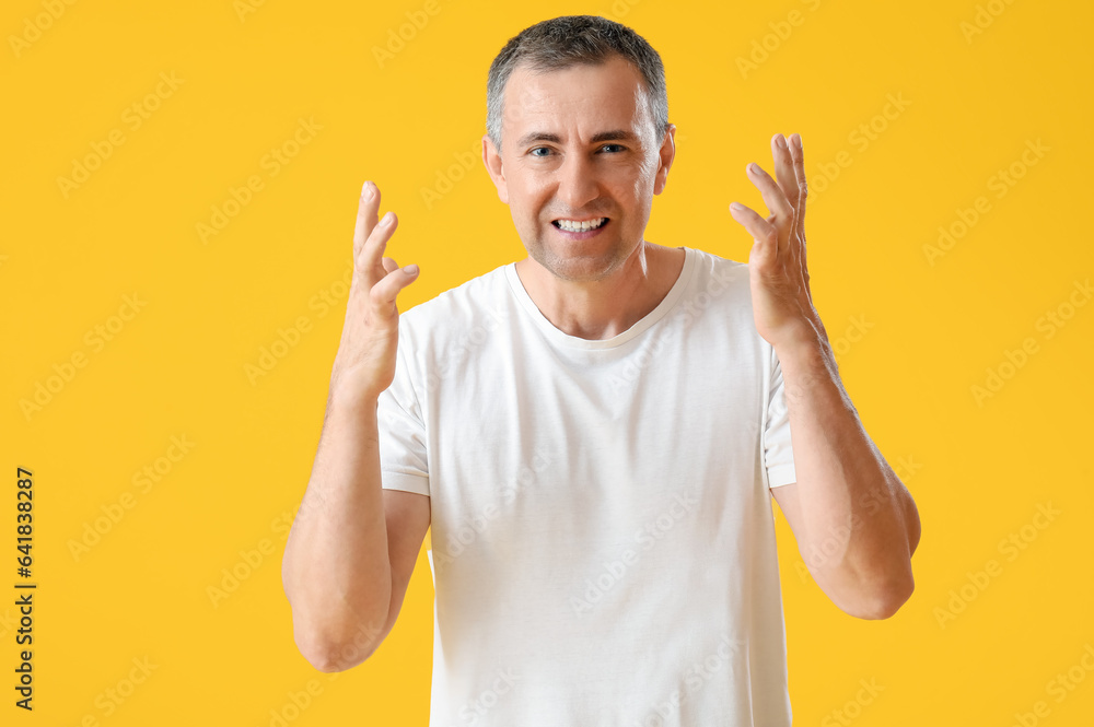 Portrait of angry mature man on orange background