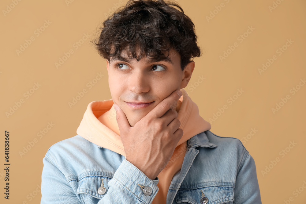 Portrait of pondering young man on beige background