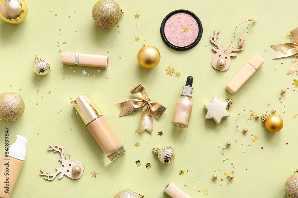 Composition with decorative cosmetics and golden Christmas decor on light yellow background