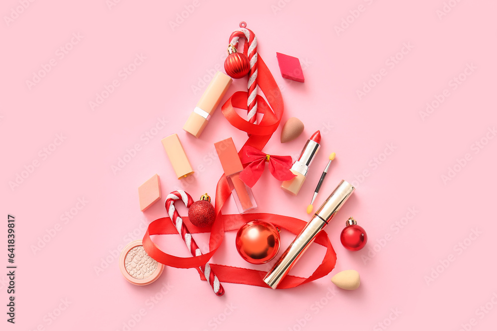 Christmas tree made of makeup products and red decor on pink background