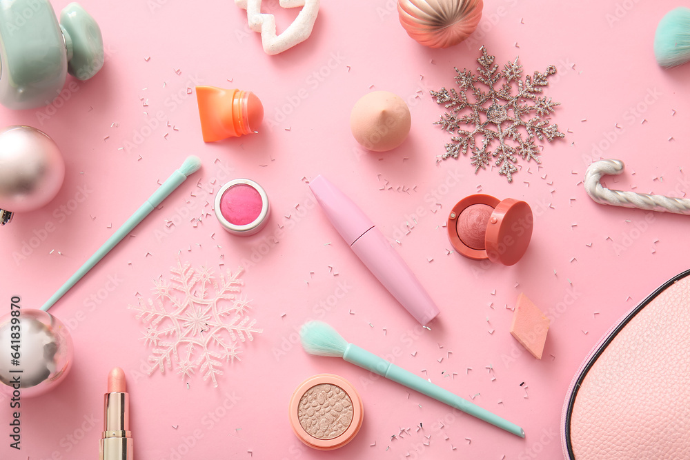 Makeup products and Christmas decorations on pink background