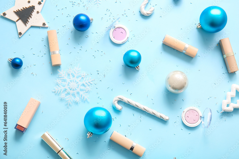 Composition with makeup products and Christmas balls on blue background