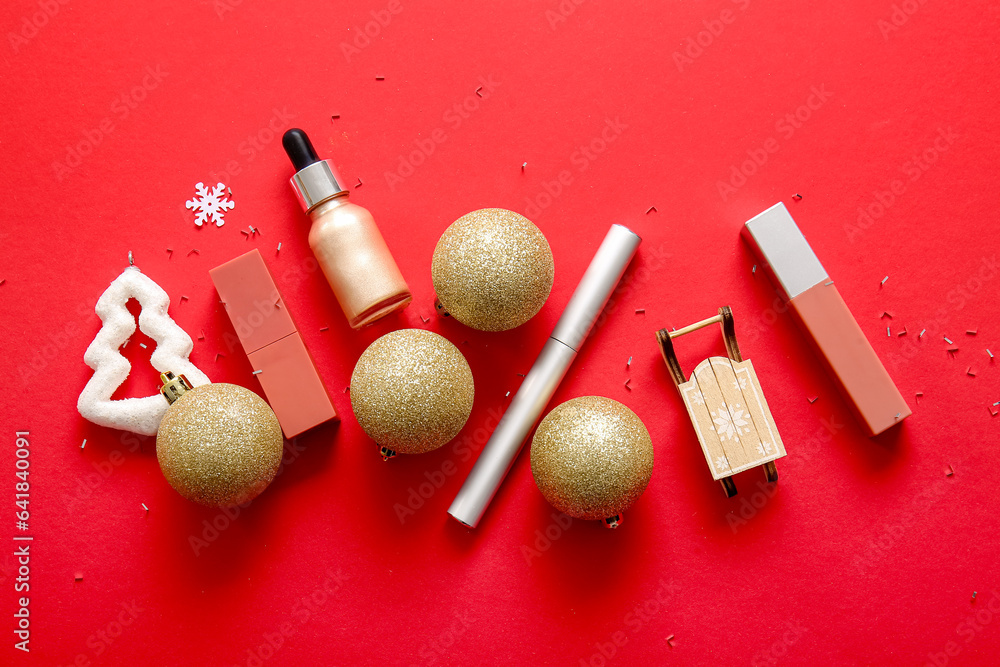 Composition with decorative cosmetics and Christmas decor on red background