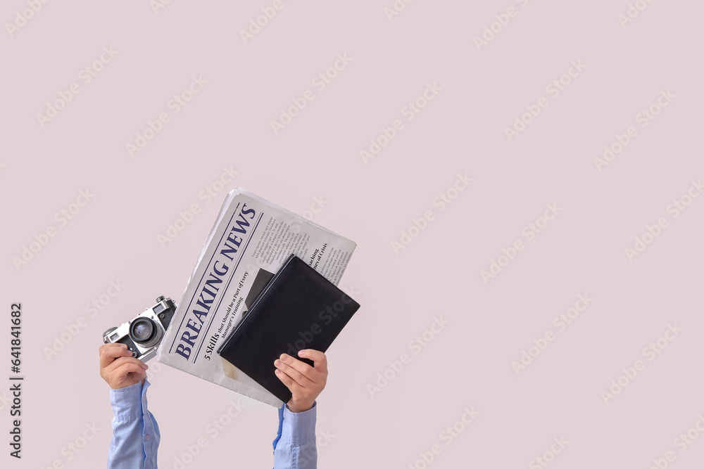 Female with newspaper, notebook and photo camera on light background