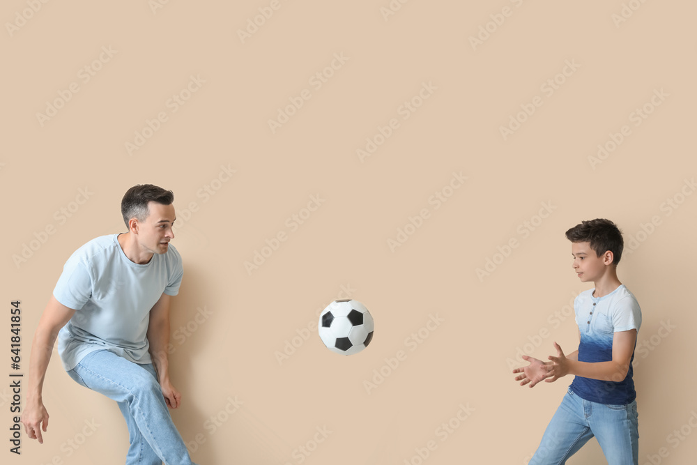 Little boy with his dad playing football on beige background