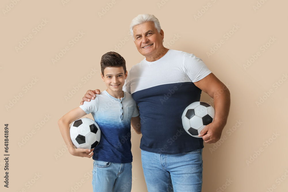 Little boy with his grandfather and soccer balls on beige background