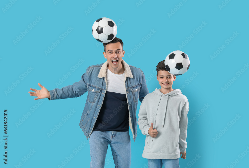 Little boy and his father playing with soccer balls on blue background