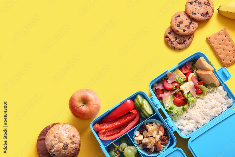 Lunchboxes with different delicious food on yellow background