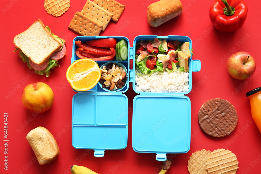 Lunchboxes with different delicious food on red background