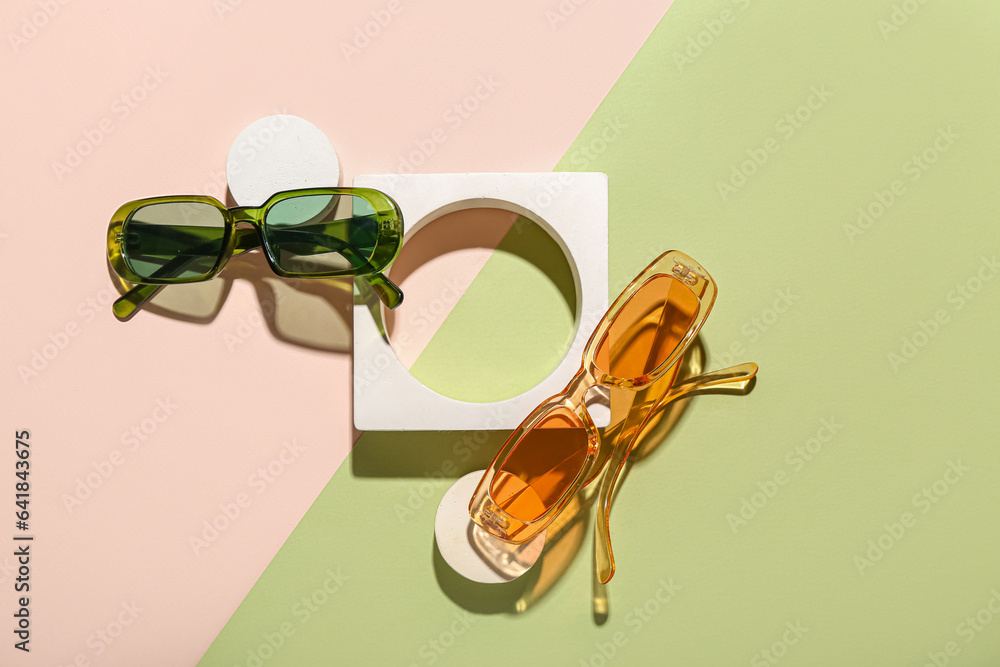 Decorative podiums with stylish sunglasses on colorful background