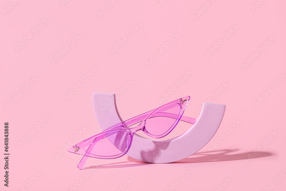 Decorative podium with stylish sunglasses on pink background