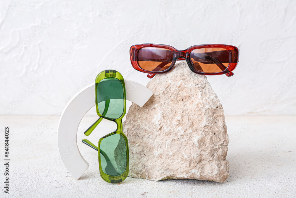 Decorative podium and stone with stylish sunglasses on white background