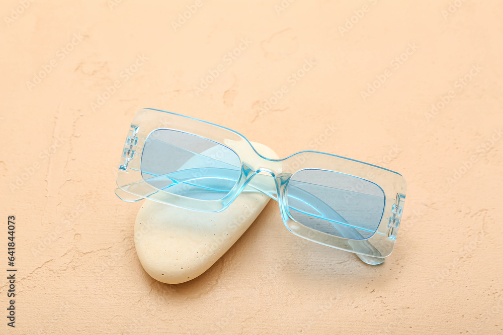 Stone with stylish sunglasses on orange background